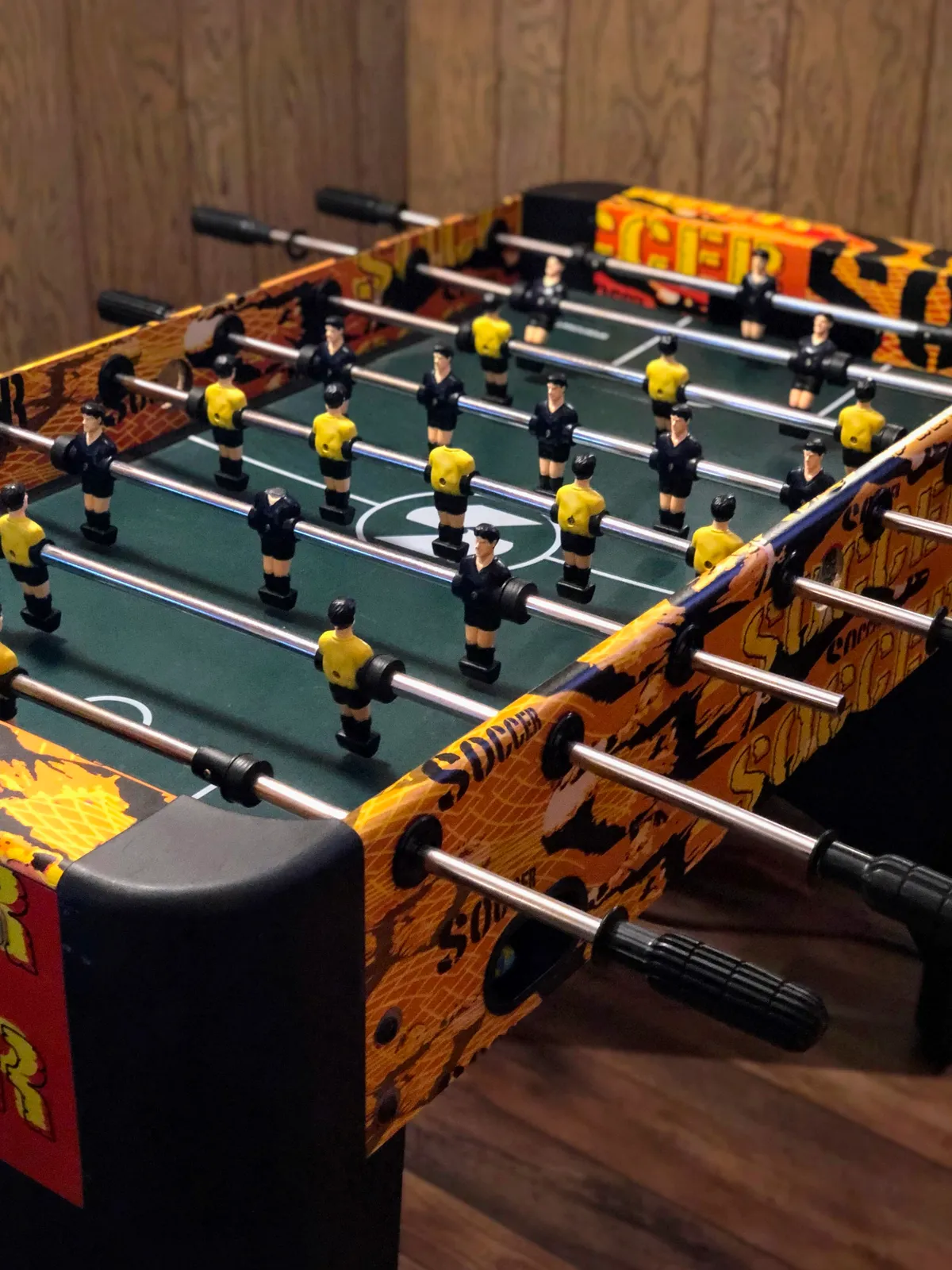 A vibrant foosball table sits center stage, its brightly colored player figurines ready for action. The surrounding area is well-lit and designed for energetic play, inviting guests to jump into friendly matches.