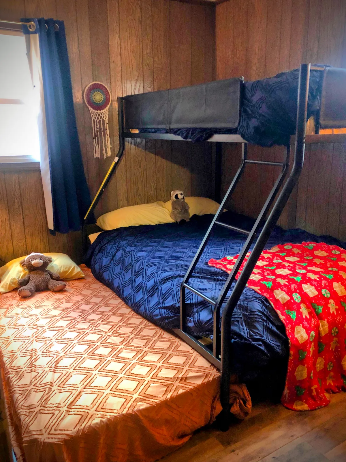 A cheerful kids' room showcasing a twin-over-full bunk bed with playful bedding, stuffed animals, a dreamcatcher, and toys. The space feels welcoming and fun, ideal for children’s rest and play.