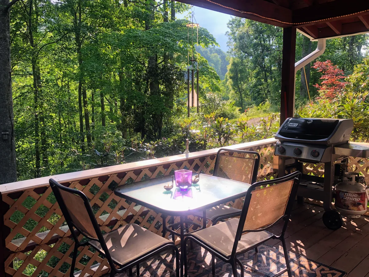 An outdoor dining table set on a patio, with a grill nearby and lush greenery all around. The table is ready for meals, and the space is perfect for gatherings—whether for sunset dinners or lively grill nights under the open sky.