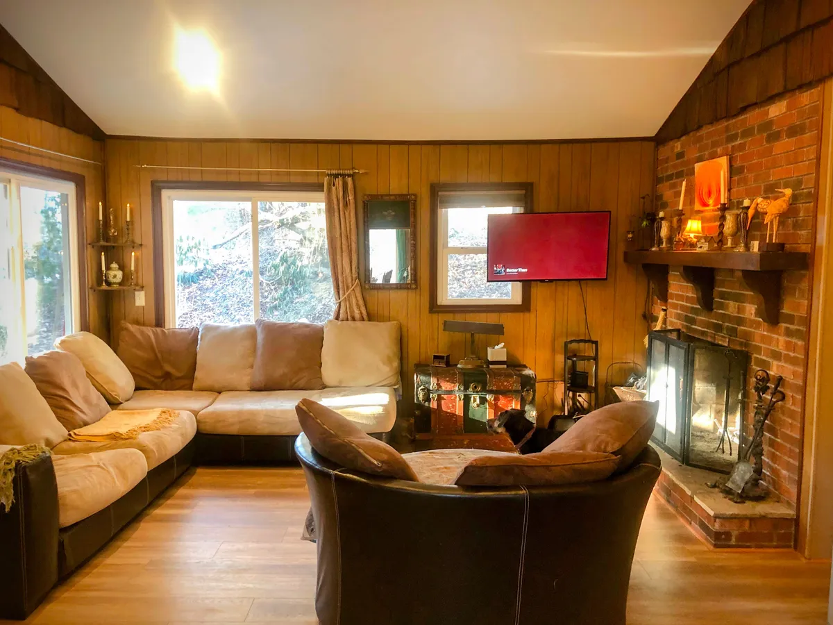 A living room with a spacious sectional sofa, fireplace, TV, and coffee table. The ambiance is inviting, with space for relaxation and additional sleeping options for groups.